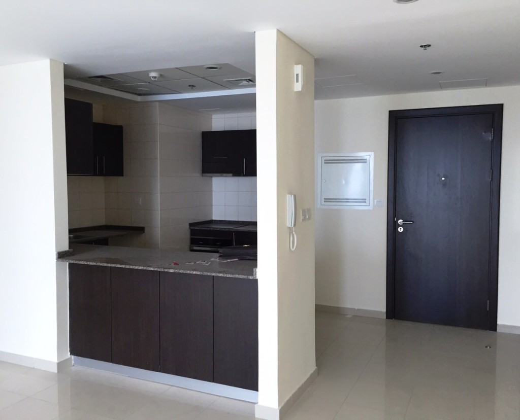 Before — empty kitchen with dark cabinets and breakfast bar