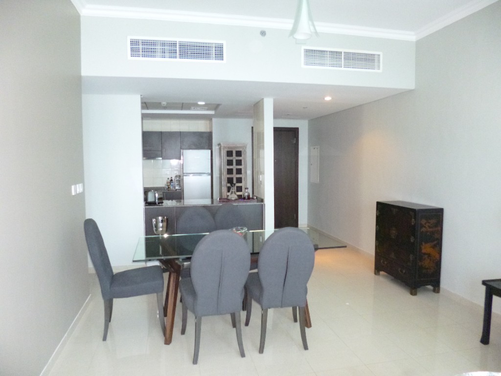 Before — open living and dining with glass table and kitchen beyond